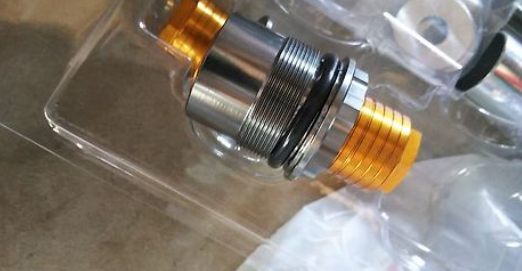 Close-up of a metallic fitting with gold and silver colors on a clear background