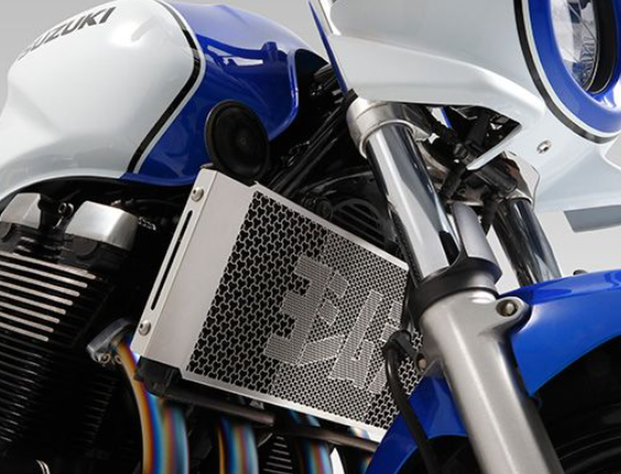 Close-up of a motorcycle radiator with 'Ferari' branding on a blue and white Suzuki motorcycle.