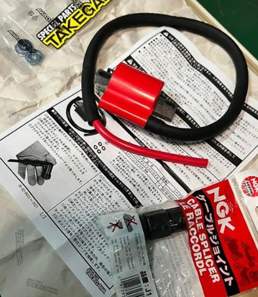 Red and black electrical connector on a newspaper with NGK branding visible