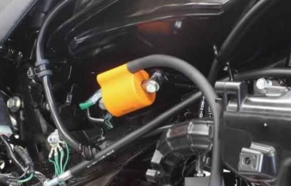 Close-up of a motorcycle's fuel tank cap with wiring and components.