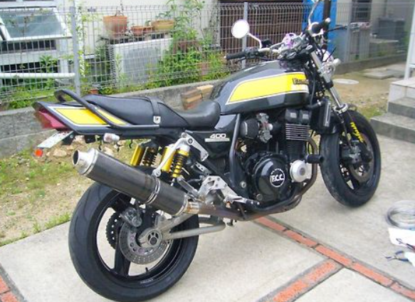 Motorcycle parked on a concrete surface with a grassy area and building in the background