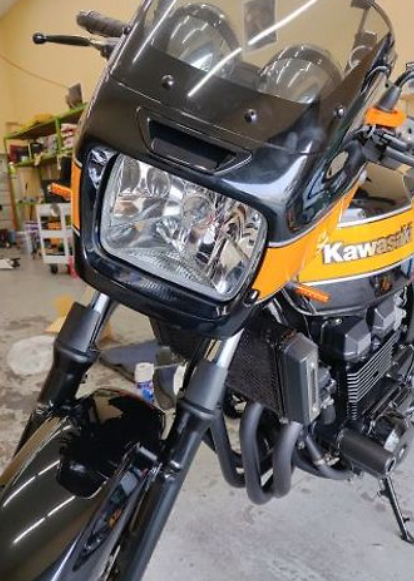 Close-up of a Kawasaki motorcycle headlight and front section in a garage.