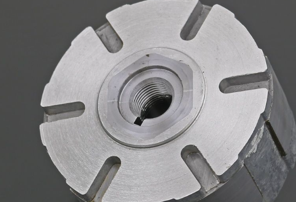 Close-up of a metallic cylindrical component with threaded center on a dark background