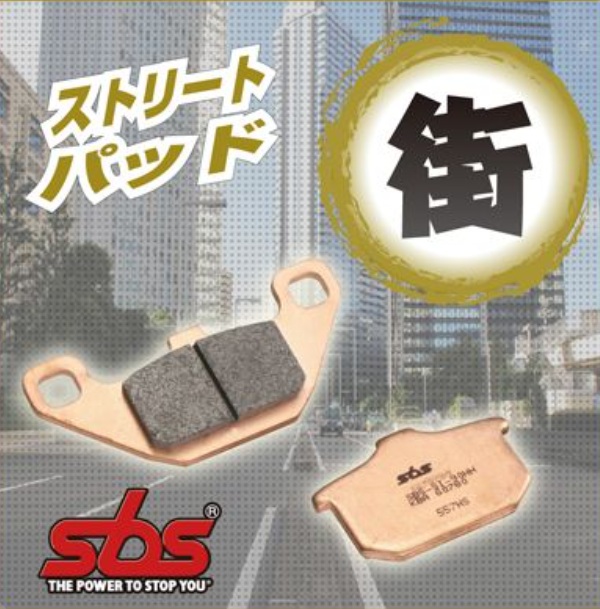 Brake pads with SBS logo and Japanese text on a blurred cityscape background