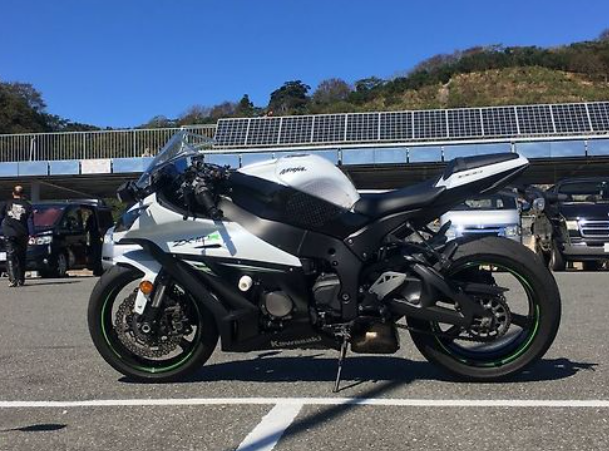 White and black motorcycle on a road with solar panels in the background