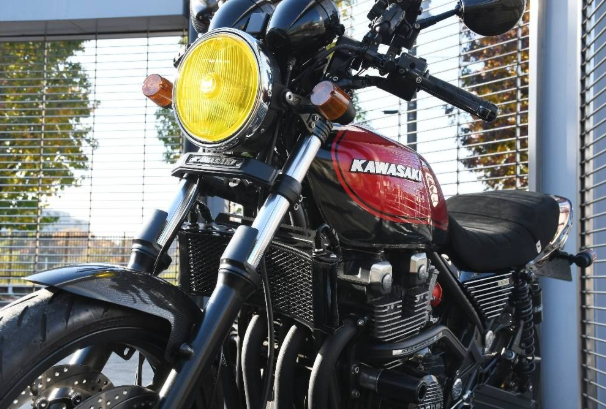 Kawasaki motorcycle with a yellow headlight in front of a wire fence.