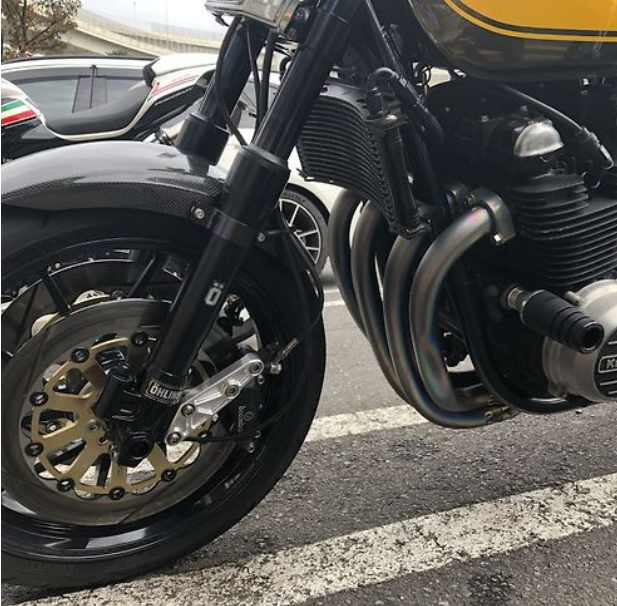 Close-up of a motorcycle's front wheel and engine on a street.