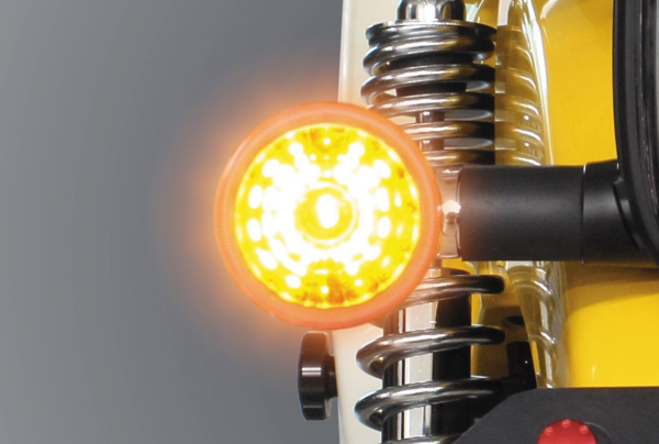 Close-up of a yellow light bulb with a metallic spring on a gray background