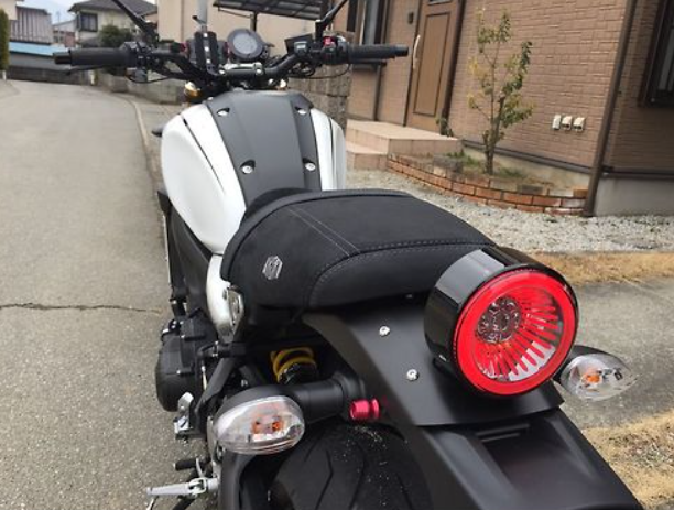 Motorcycle with a red tail light parked on a street.