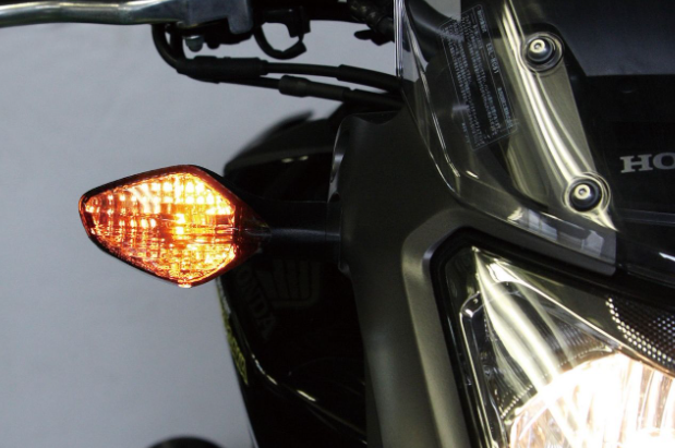 Close-up of a motorcycle's headlight and turn signal on a gray background