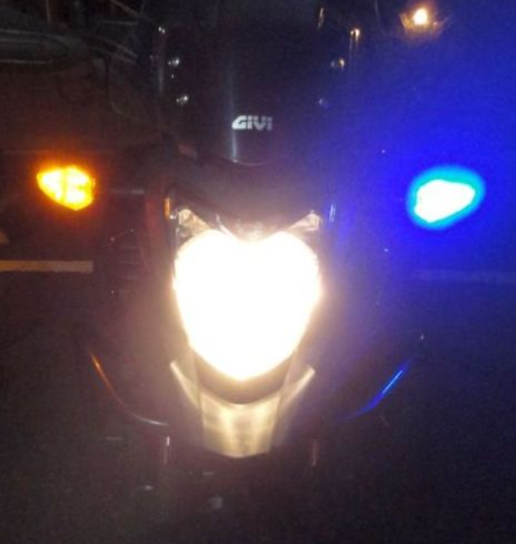 Close-up of a motorcycle headlight with visible brand logo at night.