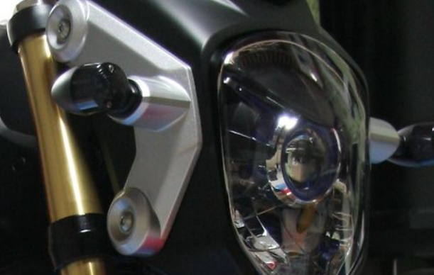 Close-up of a motorcycle headlight and gold suspension fork
