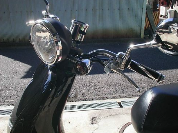 Close-up of a motorcycle's headlight and handlebar on a street.