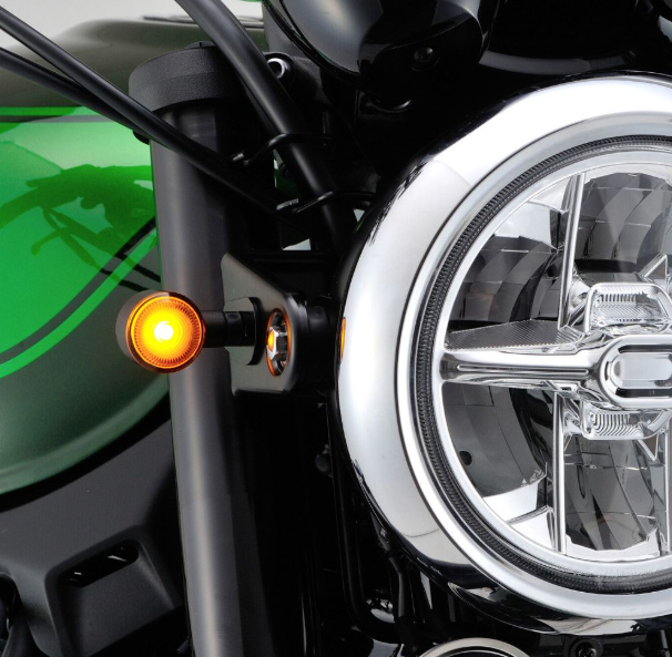 Close-up of a motorcycle headlight and turn signal with a green background