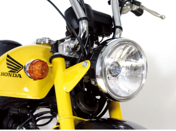 Close-up of a yellow Honda motorcycle headlight and front fork on a white background