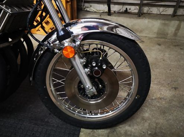 Close-up of a motorcycle wheel with a visible brand logo on a concrete floor.