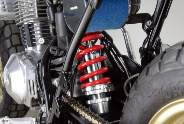 Close-up of a motorcycle suspension system with red spring and black tire.
