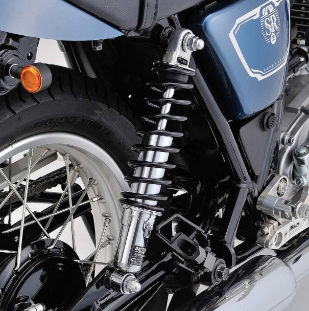 Close-up of a motorcycle's suspension system with a brand logo on a blue background.