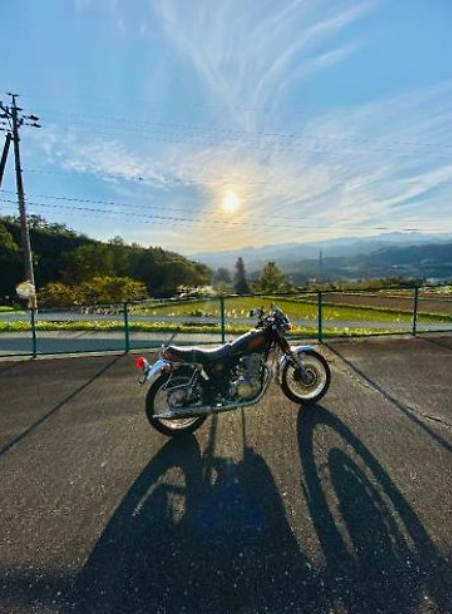 Motorcycle on a road with a scenic background of mountains and sun.