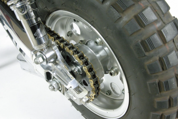 Close-up of a motorcycle wheel with chain and tire on a white background