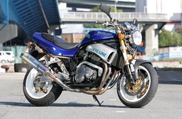 Blue and black motorcycle on a road with buildings in the background