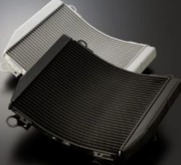 Two car radiators, one black and one white, on a dark background