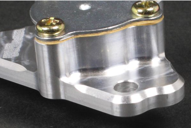 Metal mechanical component with gold screws on a dark background