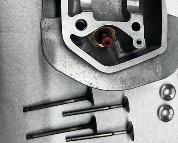 Car engine parts including a head gasket and valves on a metallic surface