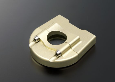 Beige metal component with a central hole on a dark background