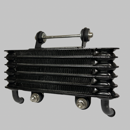 Close-up of black finned oil cooler core for Kawasaki KZ1000 Z1 Z2, showing dual mounting bolts and top stabilizer bar.