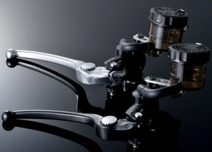 Close-up of motorcycle brake levers on a reflective surface with a dark background