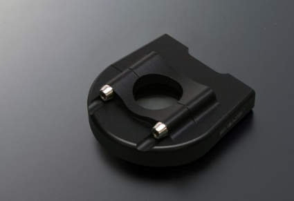 Black plastic component with metallic screws on a dark gray background