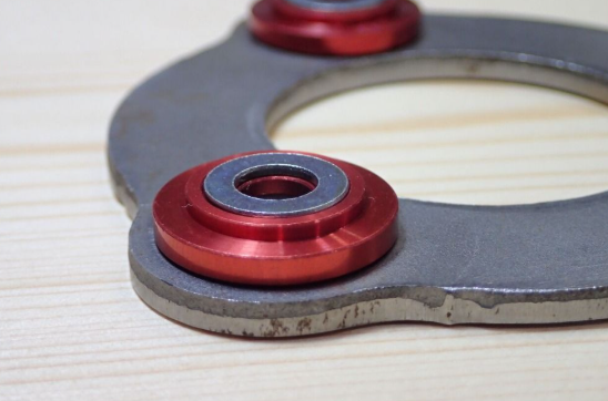 Close-up of a metal component with red washers on a wooden surface