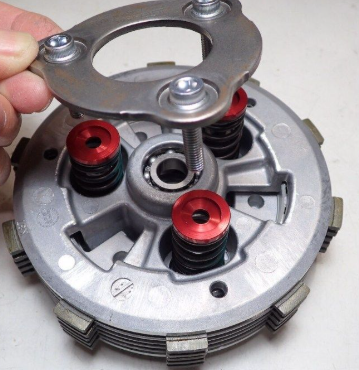 Mechanical component with red springs and metal parts on a white background