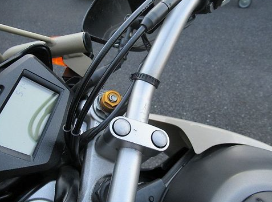 Close-up of a motorcycle handlebar with control buttons and display.