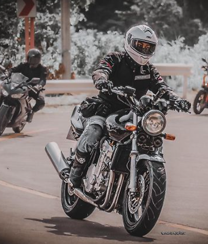 Person riding a motorcycle on a road with other riders in the background