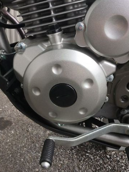 Close-up of a motorcycle engine and clutch lever on a textured surface