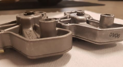 Metal mechanical component with 'DVO' branding on a textured surface