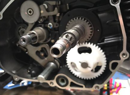 Close-up of motorcycle engine components with gears and shafts.