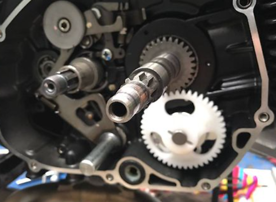 Close-up of motorcycle engine components with gears and shafts.