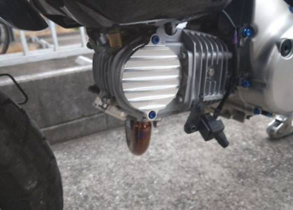 Close-up of a motorcycle engine and exhaust system on a concrete surface.
