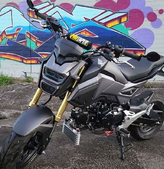 Motorcycle with gold accents parked in front of a colorful mural.