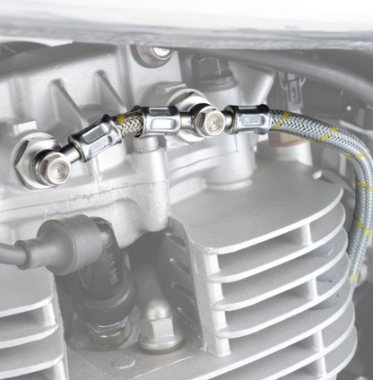 Close-up of a mechanical component with hoses and connectors on a metallic surface.