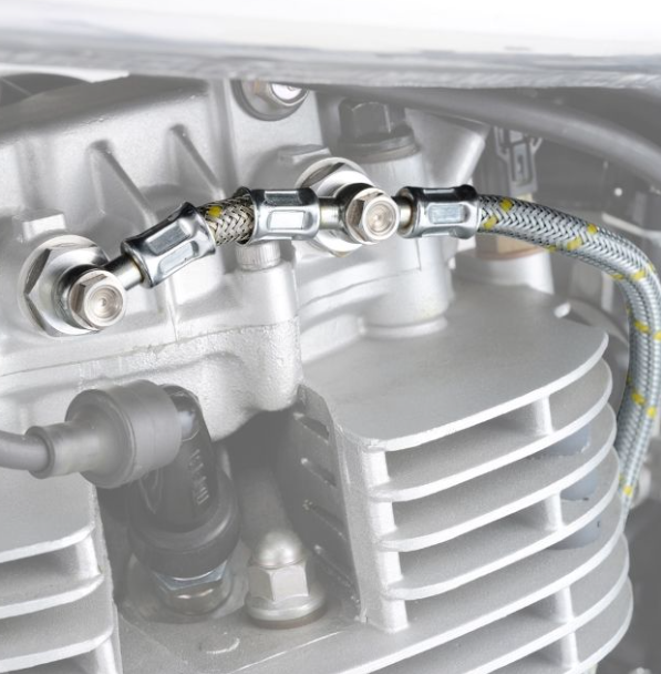 Close-up of a mechanical component with hoses and connectors on a metallic surface.