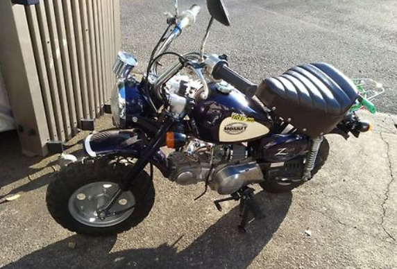Small motorcycle on a concrete surface with a building in the background