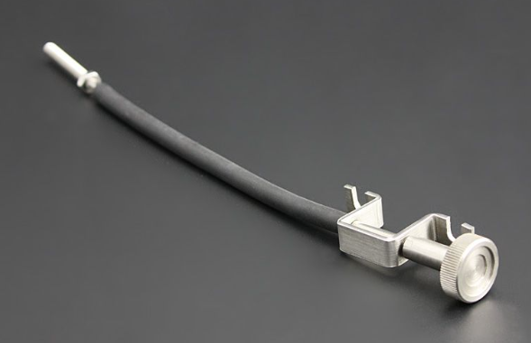 Medical instrument with a long cylindrical shaft and metal components on a dark background