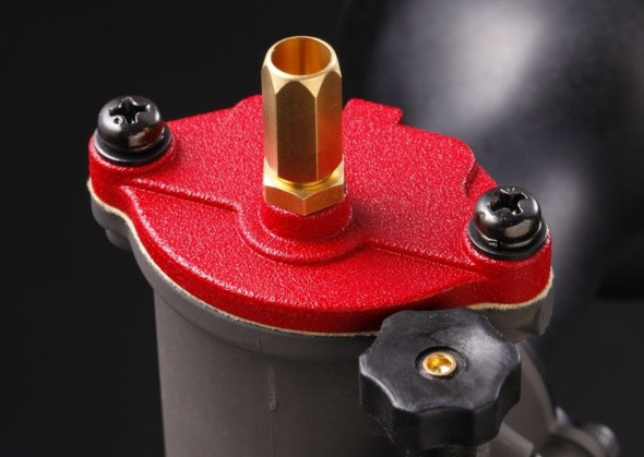 Close-up of a red and black mechanical component with gold accents on a dark background