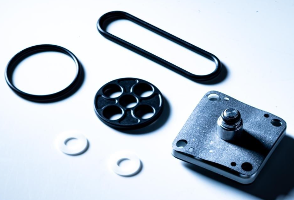 Mechanical components including a black rubber washer, metal washer, and metal gasket on a white background