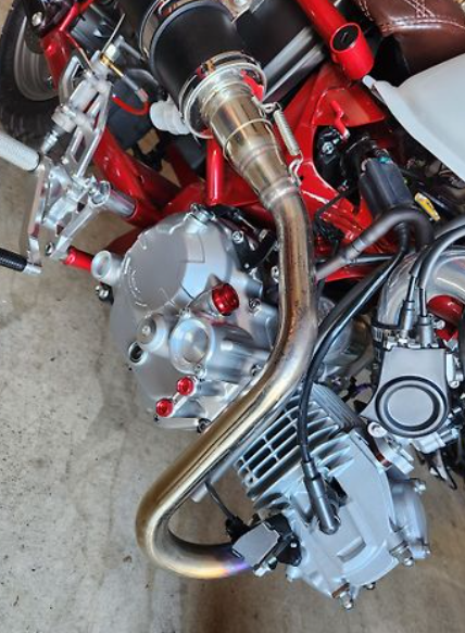 Close-up of a motorcycle engine with visible components on a concrete surface.