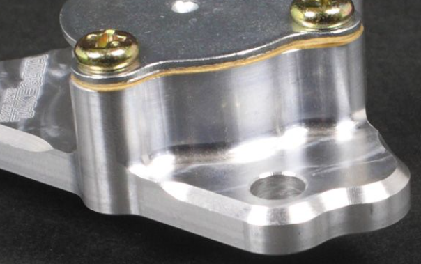Close-up of a metallic mechanical component with gold screws on a black background
